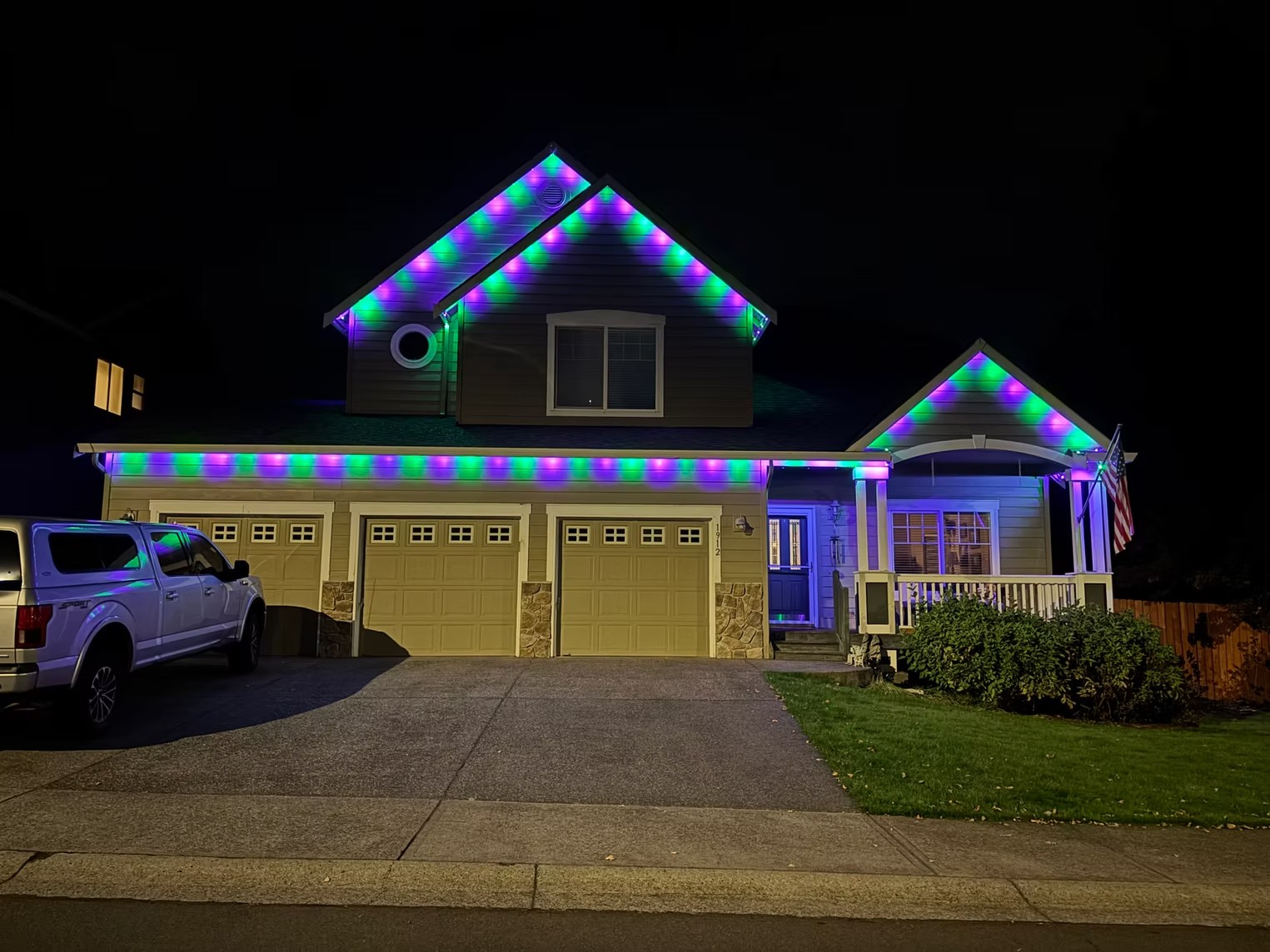 Purple and green roofline lighting on a home with a front porch
