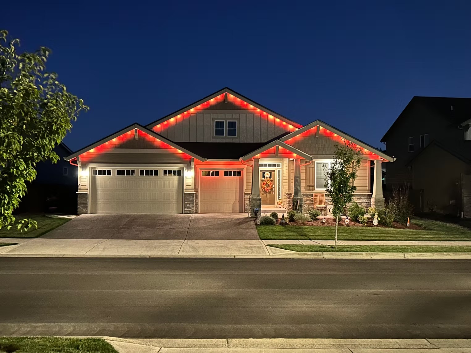 Front view of a home with red and warm-white roofline lighting at dusk