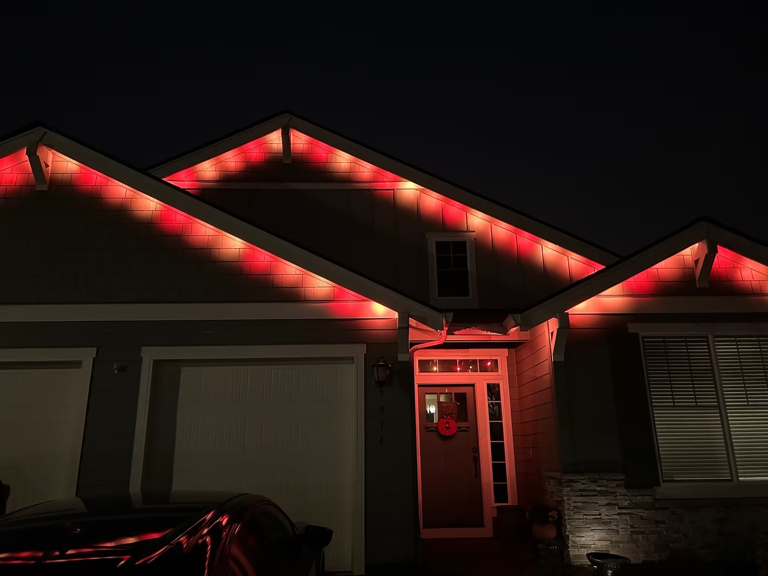 Angled close view of red lights tracing a garage roof and entryway