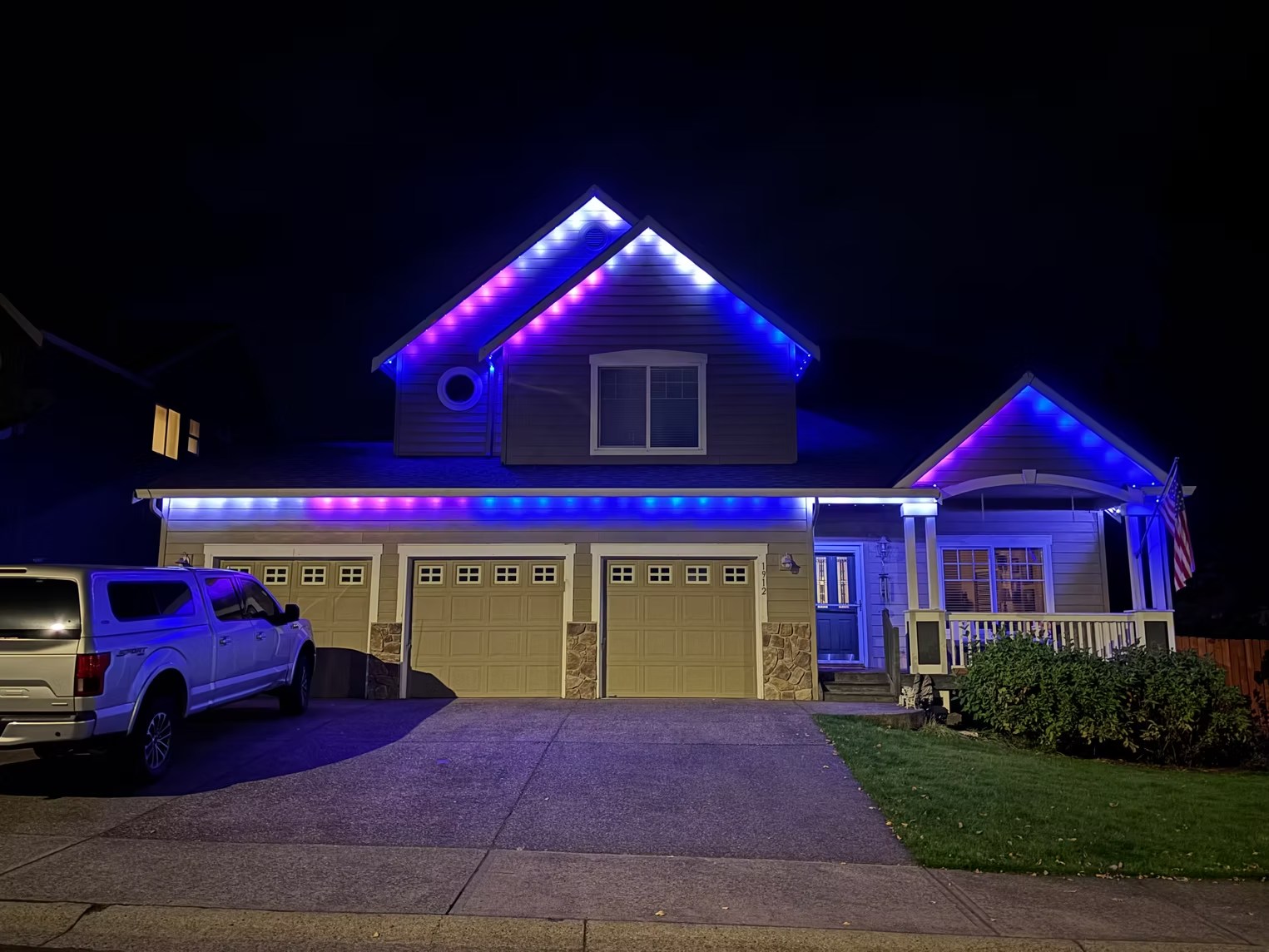 Blue and purple lighting around a two-story home and covered porch