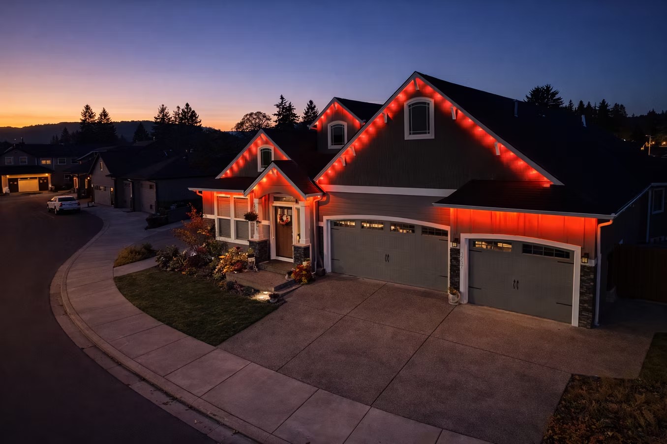 Elevated angle of a home with red roofline lighting at sunset