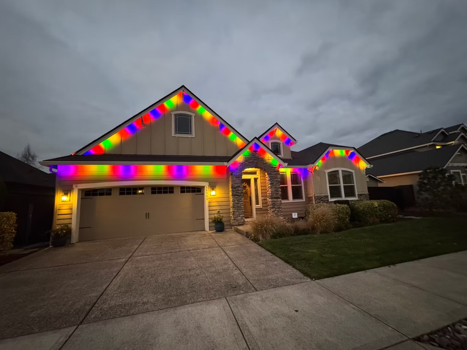 Multicolor lighting following several roof peaks on a home at dusk