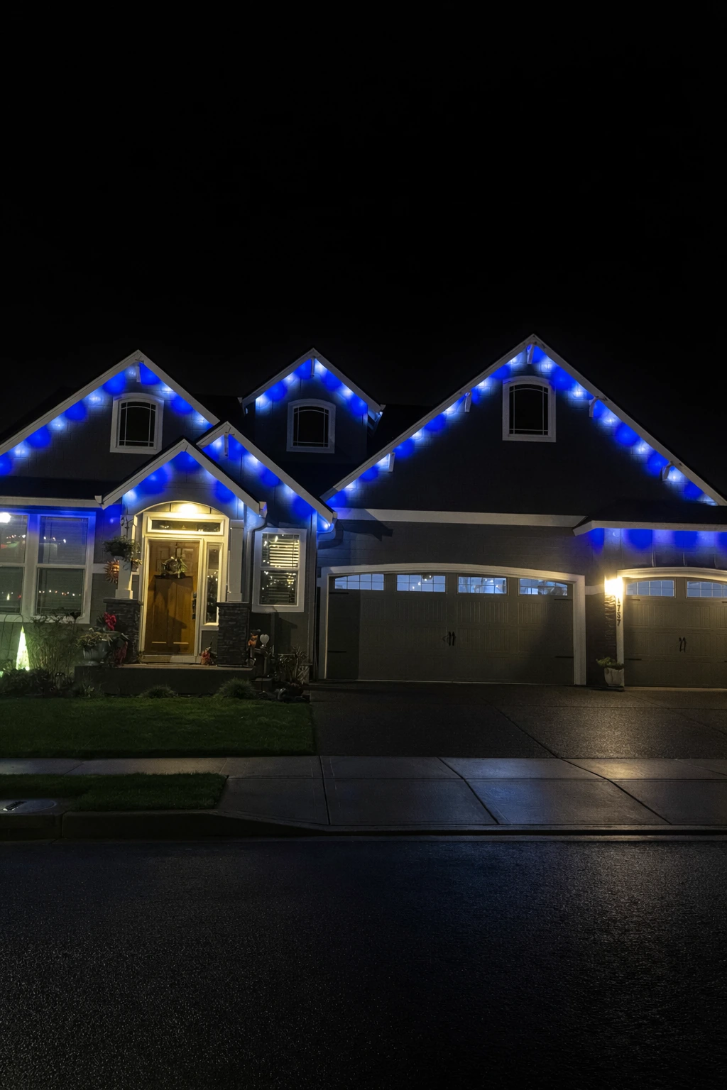 Blue and white lights outlining a home’s multiple roof peaks at night